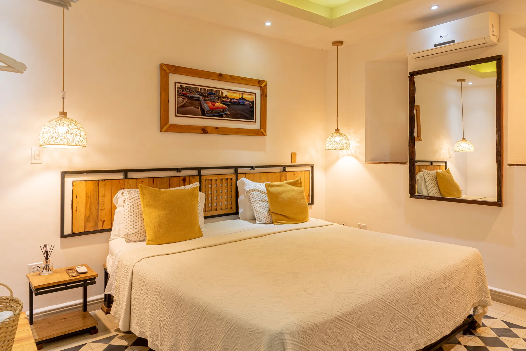 Standard Plus room with a king bed, warm pendant lights, and locally crafted wood headboard