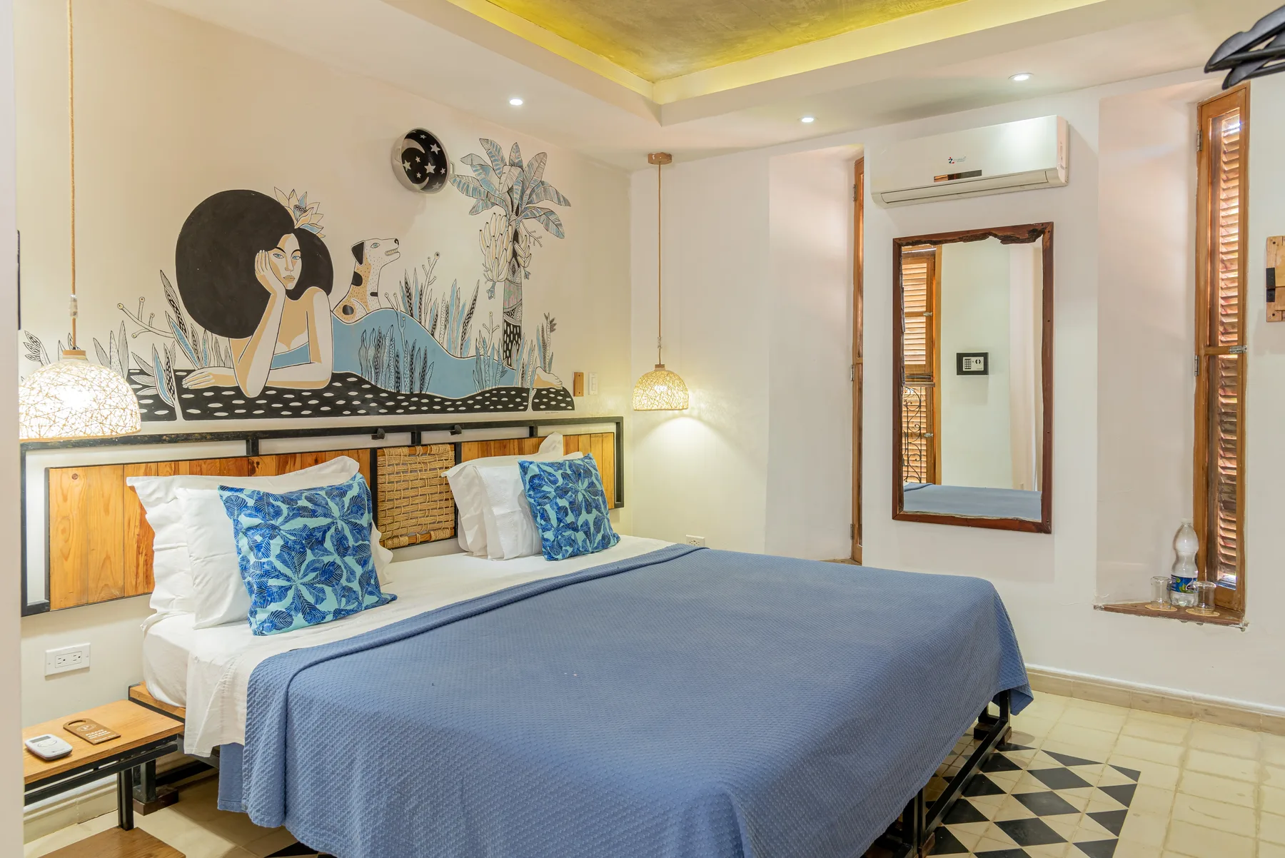 Superior room with a king bed, blue linens, handcrafted wood headboard, and Cuban wall mural